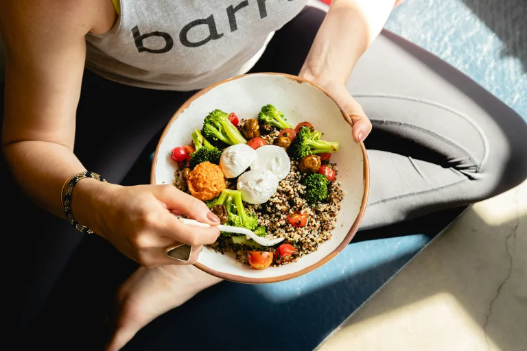 Person eating a nutritious bowl of quinoa with broccoli, tomatoes, and mushrooms, demonstrating dietitian-recommended meals for healthy eating on GLP-1 medications like Ozempic or Wegovy.